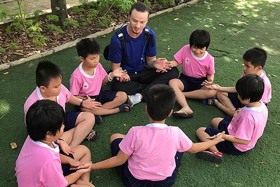 世界杯在哪里买球 student sitting in circle with children